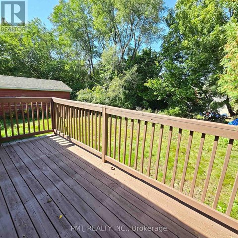 A wooden deck with a railing and trees in the background.