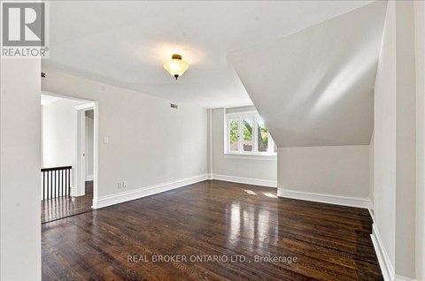 A spacious room with wood flooring and white walls.