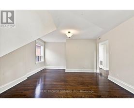 A spacious room with wooden floors and white walls.