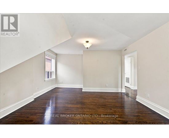 A spacious room with wooden floors and white walls.