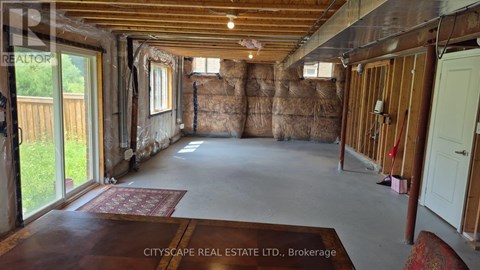 A room under construction with exposed wooden beams and insulation on the walls.