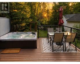 A hot tub on a deck with chairs and an umbrella.
