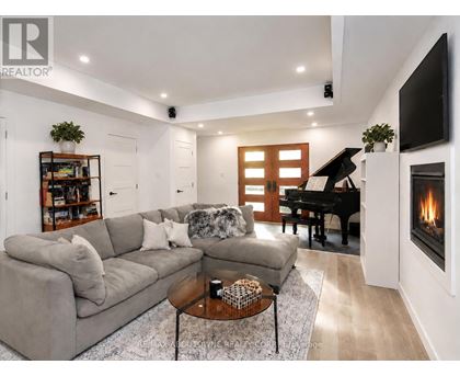 A living room with a grey couch, a coffee table, a piano, and a fireplace.