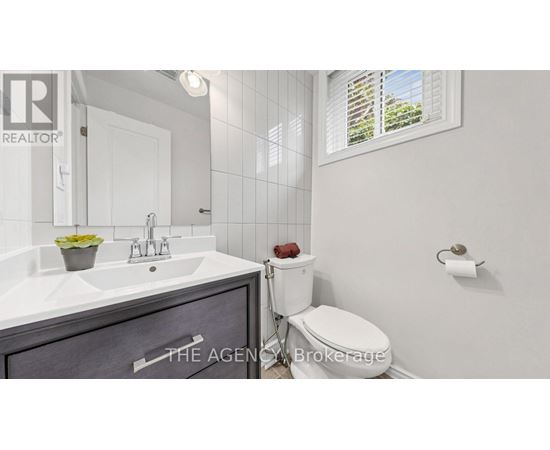 A bathroom with a sink, toilet, and a window.