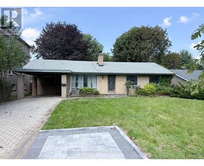 A house with a green roof and a brick driveway is for sale.