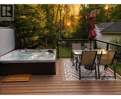 A hot tub on a deck with chairs and an umbrella.