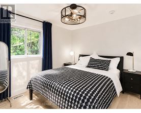 A bedroom with a black and white bedspread and a ceiling fan.