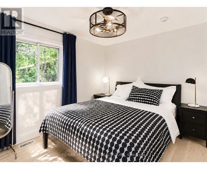 A bedroom with a black and white bedspread and a ceiling fan.