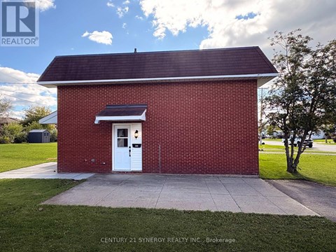 A small red brick building with a white door and a solar panel above it.