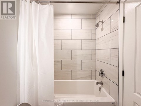 A white bathroom with a shower curtain and a bathtub.