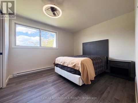 A bedroom with a bed, nightstand, and window.