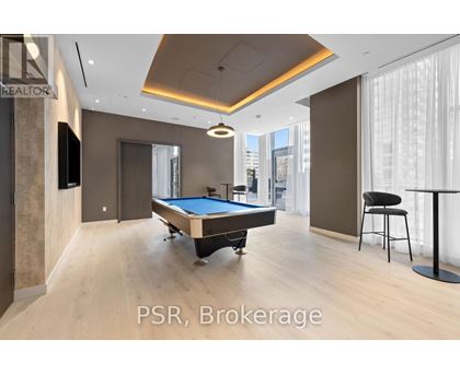 A room with a pool table and a bar stool.