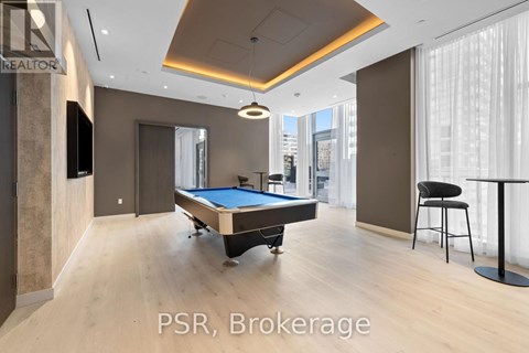 A room with a pool table and a bar stool.