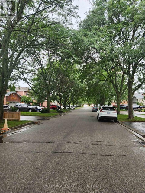 A residential street with cars parked on the side and trees lining the road.