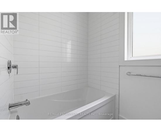 A white bathroom with a bathtub and a window.