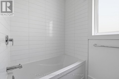 A white bathroom with a bathtub and a window.