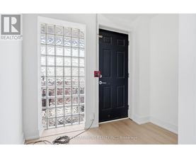 A room with a black door and a window with a grid of pictures on it.