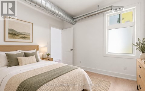 A bedroom with a bed, nightstand, and a painting on the wall.