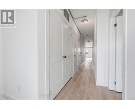 A long hallway with white walls and wood flooring.