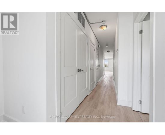 A long hallway with white walls and wood flooring.