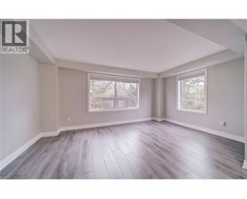 A spacious room with wood flooring and two windows.