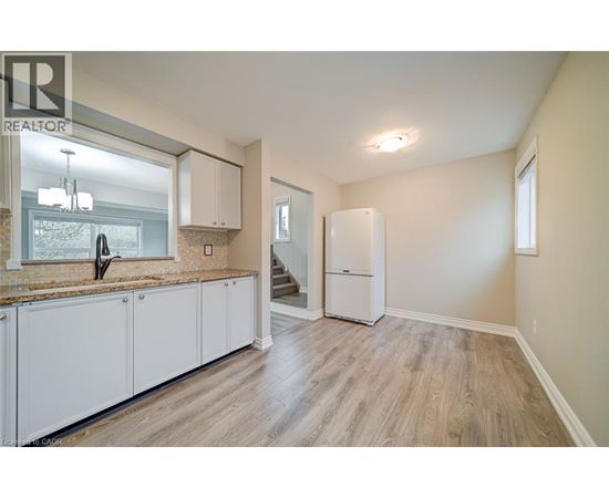 A well-lit kitchen with white cabinets and a wooden floor.