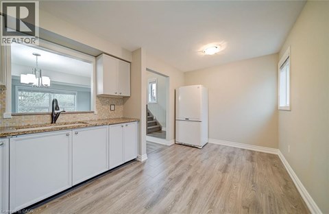 A well-lit kitchen with white cabinets and a wooden floor.