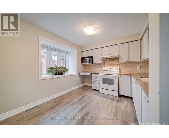A kitchen with white cabinets and a window with a view of trees.