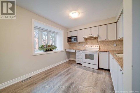 A kitchen with white cabinets and a window with a view of trees.