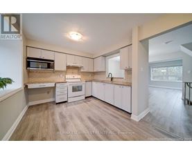 A kitchen with white cabinets and a wooden floor.