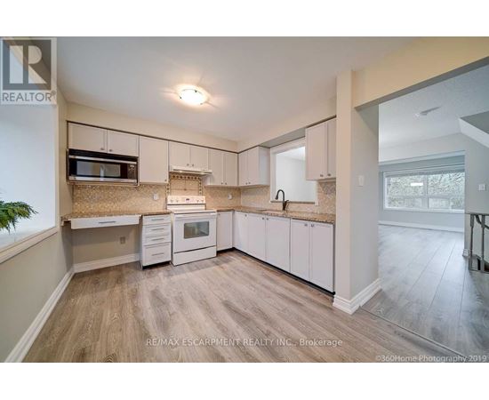 A kitchen with white cabinets and a wooden floor.