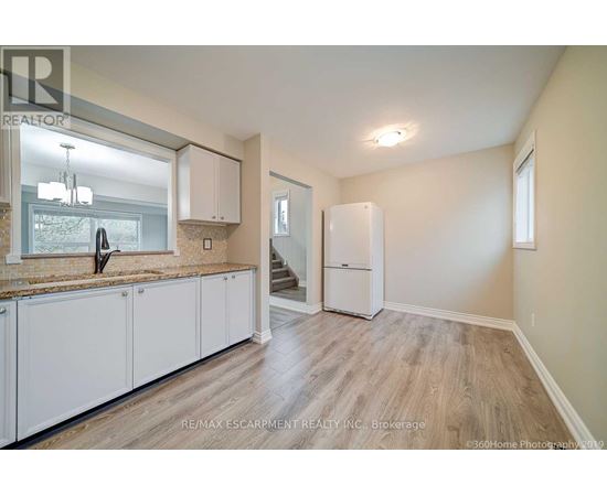 A kitchen with white cabinets and a wooden floor.