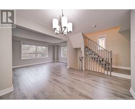 A spacious room with a staircase and a chandelier.
