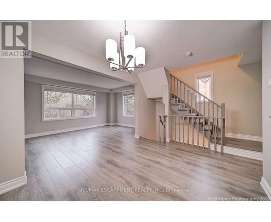 A spacious room with a staircase and a chandelier.