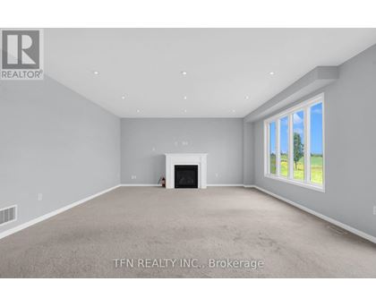 A spacious living room with a fireplace and a window showing a tree outside.