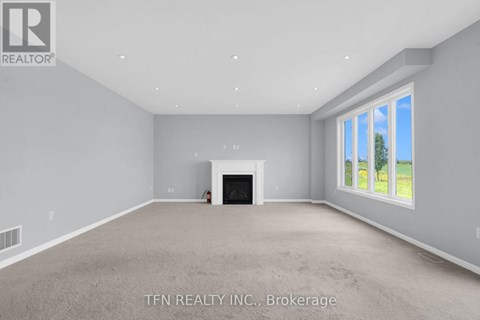 A spacious living room with a fireplace and a window showing a tree outside.