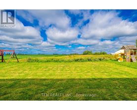 A grassy field with a swing set and a small house in the distance.