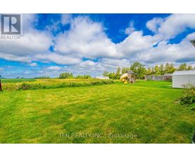 A grassy field with a house and trees in the distance.