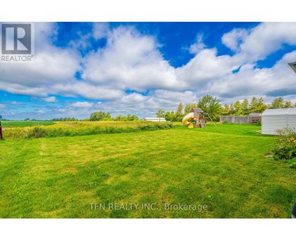 A grassy field with a house and trees in the distance.