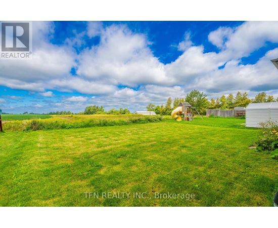 A grassy field with a house and trees in the distance.