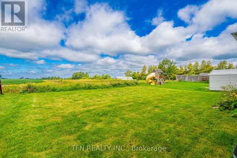 A grassy field with a house and trees in the distance.