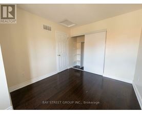 A room with wooden floors and white walls, with a door and a closet visible.