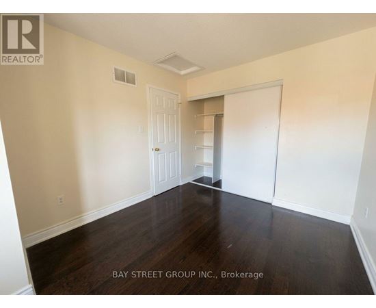 A room with wooden floors and white walls, with a door and a closet visible.