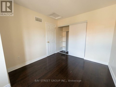 A room with wooden floors and white walls, with a door and a closet visible.
