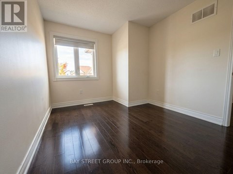 A room with a window and wooden flooring.