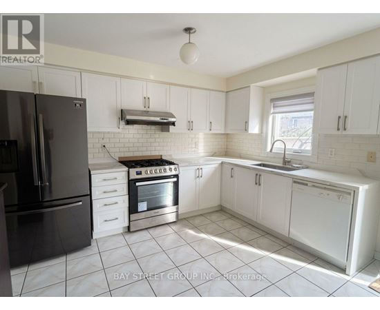 A kitchen with white cabinets and a black refrigerator.