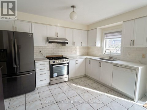 A kitchen with white cabinets and a black refrigerator.