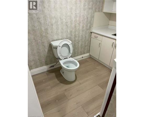 A white toilet in a small bathroom with wooden flooring.