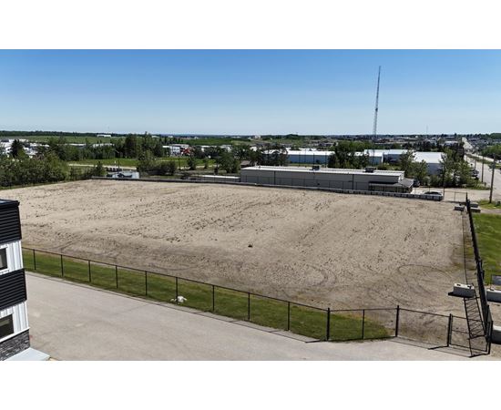 A large, empty field with a fence and a building in the background.