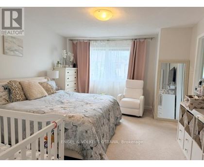 A bedroom with a white bed and a white chair.